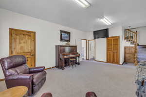 Living room featuring light carpet, baseboards, and stairway