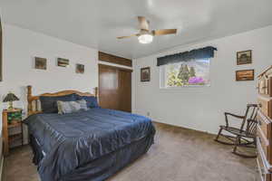 Carpeted bedroom with a closet, baseboards, and ceiling fan