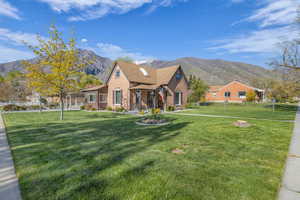View of front of house with fence, a front lawn, roof with shingles, brick siding, and a mountain view