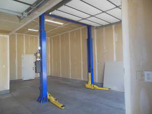View of third bay of attached garage with 10x10 door, 9000 pound vehicle lift, 12 foot ceiling and man-door to rear yard.