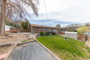 Back of property featuring a fenced backyard, terraced garden, outdoor patio and deck and storage shed.