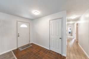 Entryway featuring arched walkways, dark wood finished floors, and baseboards