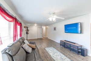 Living area featuring baseboards, a ceiling fan, and wood finished floors