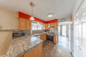 Updated kitchen featuring under cabinet range hood, stainless steel appliances, decorative backsplash, and granite counter tops.