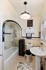 Full bath featuring tub/shower combo with European glass door, original pattern tile
