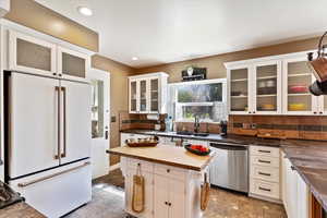 Kitchen featuring tile flooring, stainless steel dishwasher, and butcher block central island and Dekton counters