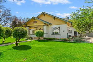 View of front Craftsman-style home with 3-tone painted brick / cedar shake shingles, lush green lawn.