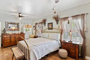 Large primary bedroom featuring hardwood flooring, 2 ceiling fans, and lots of natural light,  plantation shutters