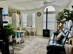 Living area featuring ceiling fan, a healthy amount of sunlight, a wood stove, and a textured ceiling