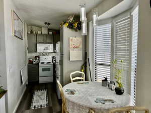 Kitchen featuring dark wood finished floors, lofted ceiling, white appliances, and plenty of natural light