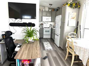 Kitchen featuring dark wood finished floors, vaulted ceiling, visible vents, white appliances, and gray cabinetry
