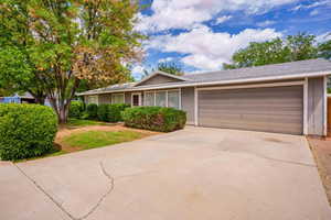 Single story home with an attached garage, a front lawn, and concrete driveway