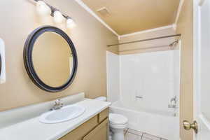 Full bathroom featuring tile patterned floors, toilet, ornamental molding, visible vents, and bathing tub / shower combination