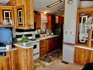 Kitchen with light countertops, visible vents, a sink, white electric range oven, and a textured ceiling