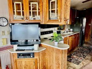 Kitchen featuring light countertops, electric range oven, glass insert cabinets, and freestanding refrigerator