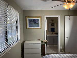 Tiled bedroom featuring ensuite bathroom, a sink, and a ceiling fan