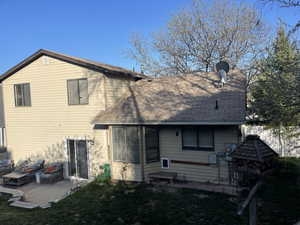 Back of house featuring roof with shingles and a patio