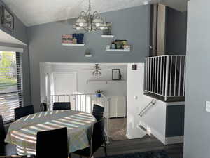 Dining area with lofted ceiling, wood finished floors, a textured ceiling, and ceiling fan with notable chandelier