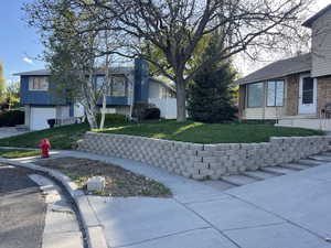 View of front side of property with brick siding, a lawn, a garage, and fence