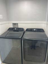 Washroom with wainscoting, washing machine and clothes dryer, a textured wall, and laundry area
