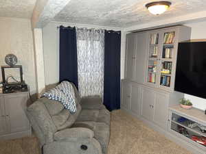 Living area with carpet flooring and a textured ceiling