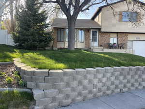 View of front of house featuring a garage, a shingled roof, fence, a front yard, and brick siding