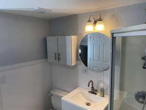 Full bathroom with wainscoting, visible vents, a shower with door, and toilet