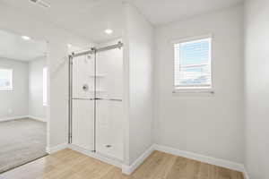 Bathroom with a shower stall, baseboards, wood finished floors, and recessed lighting