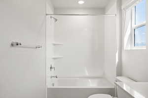 Bathroom with healthy amount of natural light, toilet, and bathtub / shower combination