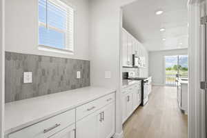 Kitchen with gas range oven, stainless steel microwave, recessed lighting, light wood-style floors, and white cabinetry