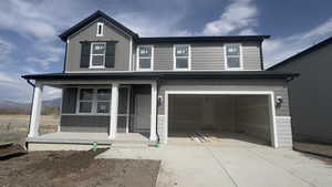 View of front of property with board and batten siding, a garage, driveway, a porch, and a mountain view