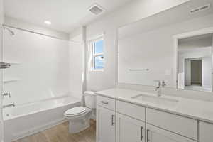 Bathroom with toilet, wood finished floors, vanity, shower / washtub combination, and recessed lighting