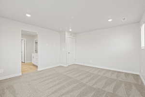 Empty room featuring light colored carpet, recessed lighting, and baseboards