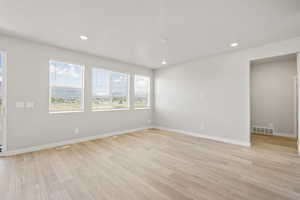 Unfurnished room featuring light wood finished floors, baseboards, and recessed lighting