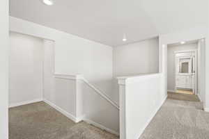 Hall featuring an upstairs landing, carpet flooring, recessed lighting, and baseboards