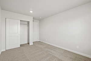 Unfurnished bedroom featuring light carpet, baseboards, a closet, and recessed lighting