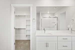 Full bath with a stall shower, double vanity, and a spacious closet