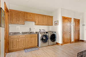 Large mudroom/laundry room featuring washing machine and clothes dryer, a sink, cabinet space, granite countertops, under counter lighting
