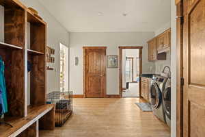 Large mudroom/laundry area with built-in knotty alder storage unit with bench, separate  linen and broom closets