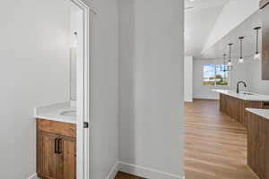 Bathroom featuring two vanities, baseboards, wood finished floors, and a sink