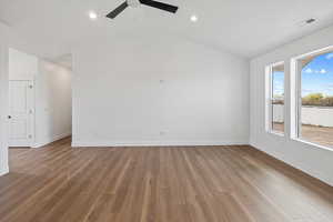 Empty room with ceiling fan, lofted ceiling, wood finished floors, and baseboards