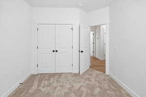 Unfurnished bedroom with carpet, a closet, and baseboards