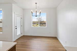 Unfurnished dining area featuring light wood-type flooring, visible vents, baseboards, and an inviting chandelier