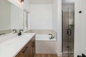 Bathroom featuring a shower stall, a garden tub, vanity, and wood finished floors