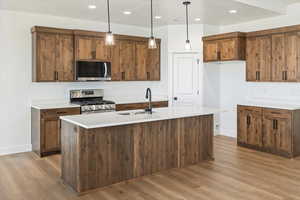 Kitchen with light wood-style flooring, baseboards, stainless steel appliances, and a sink