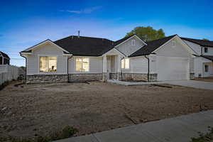 View of front facade featuring driveway, stone siding, fence, a garage, and a shingled roof