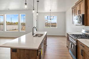 Kitchen with stainless steel appliances, visible vents, a sink, baseboards, and light wood-style flooring