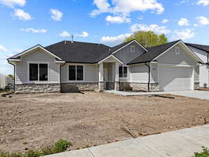 Craftsman inspired home with fence, stone siding, driveway, and a garage