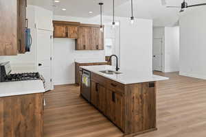Kitchen with stainless steel dishwasher, range with gas cooktop, a sink, baseboards, and light wood-style floors