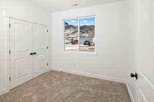 Unfurnished bedroom featuring light carpet, a mountain view, baseboards, visible vents, and a closet